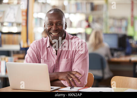 Von ausgewachsenen männlichen Kursteilnehmer mit Laptop in der Bibliothek Portrait Stockfoto