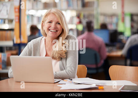 Der geschlechtsreifen weiblichen Kursteilnehmer mit Laptop in der Bibliothek Portrait Stockfoto