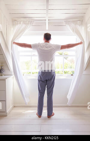 Rückansicht des Menschen Eröffnung Vorhänge und Blick Aus Fenster Stockfoto