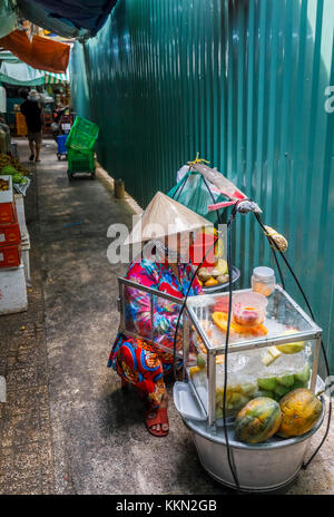 Lokale Lebensweise: Frau mit einem konischen Hut verkauft Lebensmittel in Packtaschen, Binh Tay ODER Hoa Binh Markt, Chinatown (Cholon), Saigon (Ho Chi Minh Stadt), Südvietnam Stockfoto