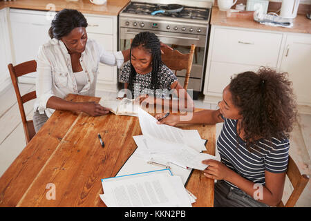 Mutter, zwei Töchter Sitzen am Tisch mit Hausaufgaben Stockfoto