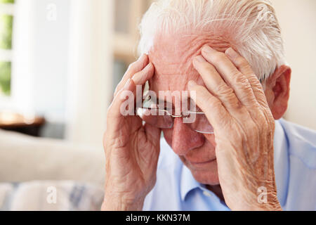 Älterer Mann sitzt auf einem Sofa zu Hause, die unter Depressionen leiden Stockfoto