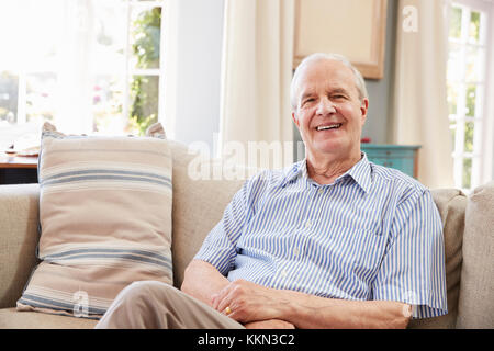 Portrait Of Smiling Senior Mann zu Hause auf dem Sofa sitzen Stockfoto