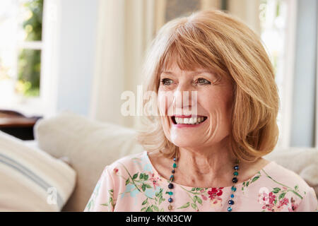 Lächelnd Senior Frau sitzt auf einem Sofa zu Hause Stockfoto