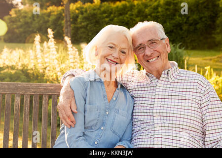 Senior Paar Sitzen auf der Gartenbank in der Abendsonne Stockfoto