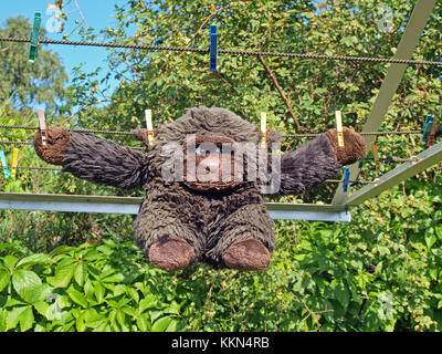 Alte vintage Soft toy doll Monkey nach dem Waschen trocknen auf Wäscheservice Seil in der Nähe ist Stockfoto