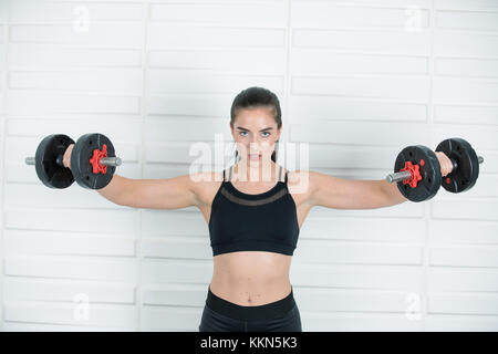 Melissa, ist ein Modell und Fitness Trainer mit freien Gewichten zu erhalten ihr Gut gedämpft. Stockfoto