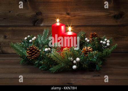 Zweiten Advent - geschmückt Adventskranz mit zwei roten brennenden Kerzen auf einem hölzernen Hintergrund. Stockfoto