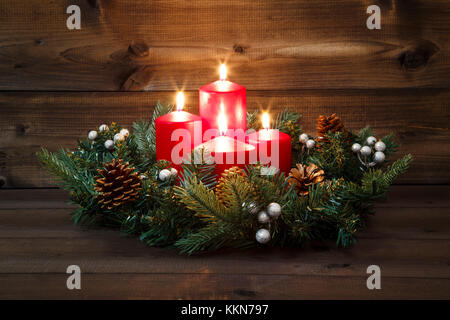 Vierter Advent - geschmückt Adventskranz mit vier rote brennende Kerzen auf einem hölzernen Hintergrund. Stockfoto