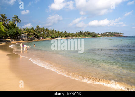 Tropischen Sandstrand und Kokospalmen um eine geschwungene Bucht, Mirissa, Sri Lanka Stockfoto