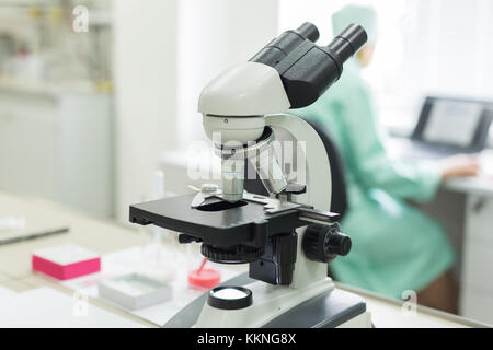 Mikroskop im Labor. Mitarbeiter am Tisch sitzen und Arbeiten am Computer. Konzept: Research Lab Stockfoto