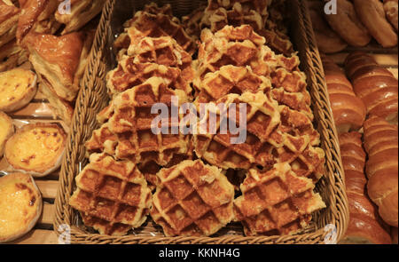 Haufen von frisch gebackenen Waffeln in einem Korb mit einem anderen köstlichen Backwaren Stockfoto