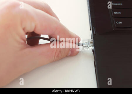 Ethernet Kabel Stecker auf dem Computer Laptop Tastatur Technologie Konzept. Hand halten Netzwerkkabel closeup. Anschluss Patchkabel RJ45 Laptop Stockfoto