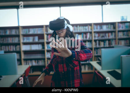 Mädchen, die ein Headset mit virtueller Realität in der Bibliothek verwenden Stockfoto