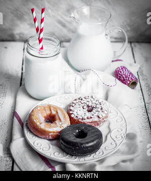 Milch und verschiedene Donuts auf der rustikalen Holzmöbeln Hintergrund Stockfoto