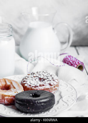 Milch und verschiedene Donuts auf der rustikalen Holzmöbeln Hintergrund Stockfoto