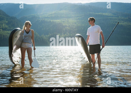 Paar mit Stand up paddleboard Wandern in Fluss Stockfoto