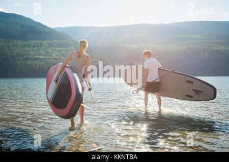 Paar mit Stand up paddleboard Wandern in Fluss Stockfoto