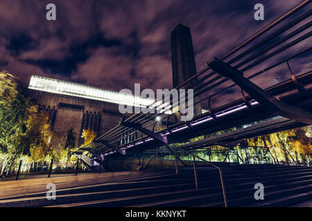 Flacher Blick auf das moderne Tate-Gebäude und die Millennium Bridge in London bei Nacht Stockfoto