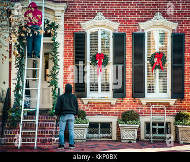 Arbeitnehmer hängen Weihnachten Kränze auf einem kolonialen Haus in Nordvirginia. Stockfoto