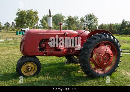 Roter Traktor Ontario Kanada alte große Reifen trichterparkt historische historische Ausrüstung Lifestyle Bauernhof außerhalb leuchtender Farben Stockfoto