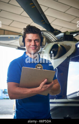 Portrait der männlichen aero Ingenieur mit Zwischenablage Durchführung prüfen auf Helikopter im Hangar Stockfoto