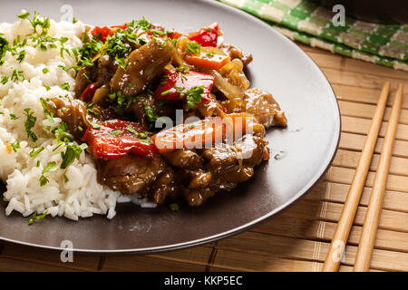 Chinesische klebrige Schweinefleisch Rinderfilet gebraten mit einem süßen und herzhaften Soße mit gekochtem Reis serviert Stockfoto