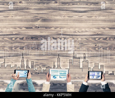 Eine Gruppe von drei Personen mit Geräten in Händen, die als Symbol der Vernetzung und Kommunikation Stockfoto