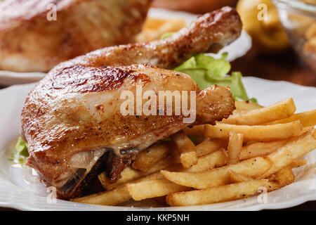 Gebratene Hähnchenkeulen mit Pommes Frites und Salat auf einen Teller Stockfoto