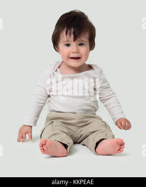 Lustige Baby auf dem Boden sitzend, über Weiß isoliert Stockfoto