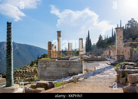 Tempel des Apollo mit einer Replik der Schlange Spalte links im Vordergrund, Delphi, Griechenland Stockfoto