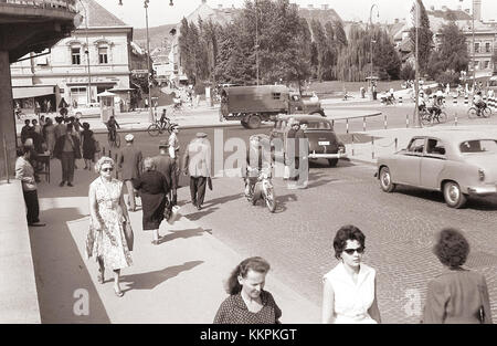 Das Bild zeigt den Promet in Glavni Trg (Hauptplatz) und die Alte Brücke in Maribor, Slowenien, im Jahr 1959. Die Szene spiegelt die soziale und kulturelle Atmosphäre der damaligen Zeit zusammen mit architektonischen Wahrzeichen der Stadt wider. Stockfoto