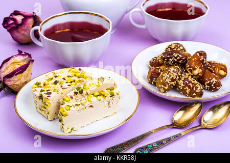 Orientalische Süßigkeiten-Halva und Termine auf einem hellen rosa Hintergrund Stockfoto