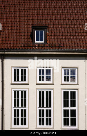 Ein altes Gebäude mit auffallend leuchtend roten Dachziegeln und hohen Fenstern. Stockfoto