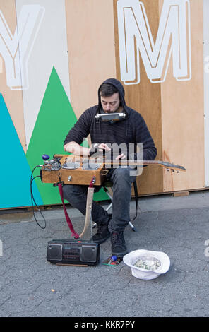 Eine one man band Musiker spielen ein hausgemachtes Instrument für Spenden außerhalb der Union Square Holiday Markt in New York Stockfoto