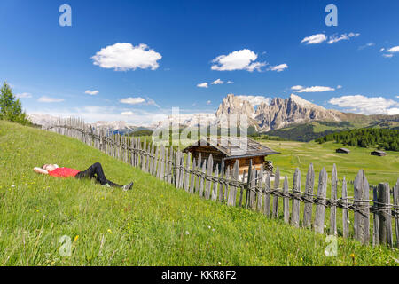 Europa, Italien, Südtirol, Bozen, Dolomiten, Wanderer ruht auf einer Wiese auf der Seiser Alm. Stockfoto