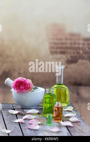 Spa und Wellness Konzept: Vorbereitung des wesentlichen Öls mit rosa Rosen, Flasche Tinktur und Mörtel auf einem Holzbrett mit allen vintage Wall Stockfoto