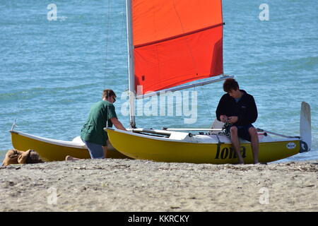 Kleine Segelyacht mit bunten Segel für den Start von zwei Jungen vorbereitet. Stockfoto