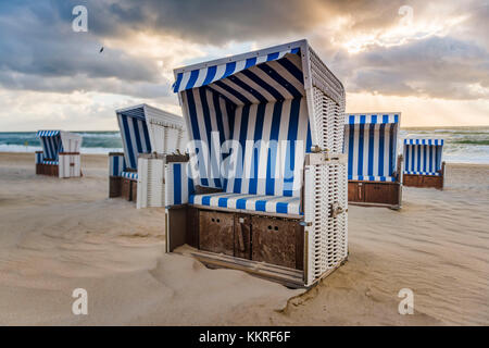 Kampen, Sylt, Nordfriesland, Schleswig-Holstein, Deutschland. Strandkorbs am Strand bei Sonnenuntergang. Stockfoto