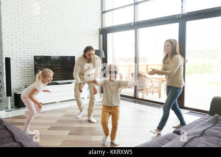 Mit verbundenen Augen wenig Junge spielt verstecken und Spiel mit der Familie suchen Stockfoto