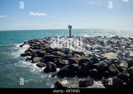 Sea Wall oder Damm gebaut, der natürlichen Felsen mit einem leuchtfeuer am Ende als Teil der Küstenschutz gegen Erosion durch Gezeiten Stockfoto