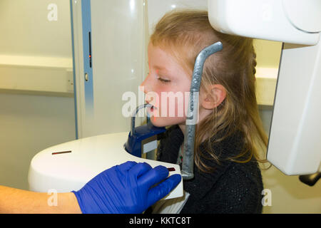 Kind im Alter von sieben Jahren bereit ist, eine zahnmedizinische Röntgensysteme Scannen, um einen Scanvorgang Panoramablick x-ray Gerät/Maschine zu haben. UK. Kind ist Model Released. (92) Stockfoto