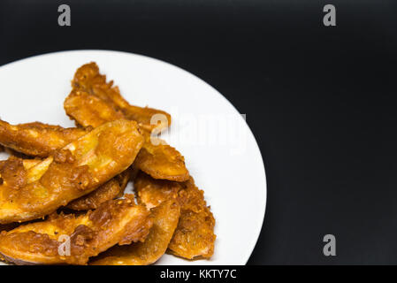 Köstliche traditionelle Golden gebratene Banane Krapfen auf weißem Schild mit schwarzem Hintergrund isoliert Stockfoto