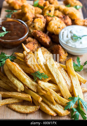 Serviert Pommes und Chicken Nuggets im Hintergrund auf Holzbrett, selektiver Fokus Stockfoto