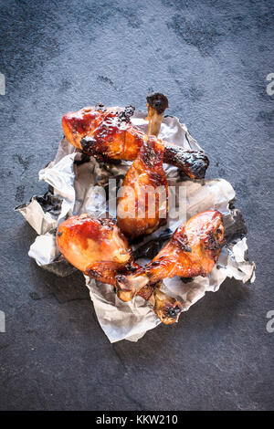 Sweet Fried Chicken Drumsticks mit Honig und Gewürzen von oben auf dunklem Hintergrund Stockfoto