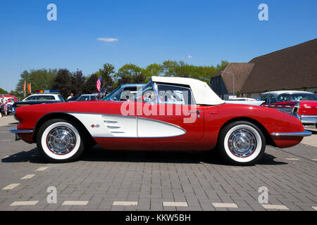 DEN BOSCH, Niederlande - 10. MAI 2016: Seitenansicht eines geparkten roten und weißen 1960er Chevrolet Corvette Roadster Oldtimer. Stockfoto