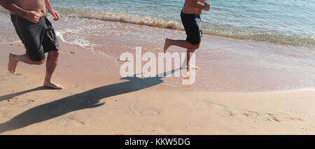 Zwei Männer laufen am Strand Stockfoto