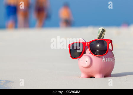 Rosa Schwein Geldbox in roten Sonnenbrillen am Strand Stockfoto