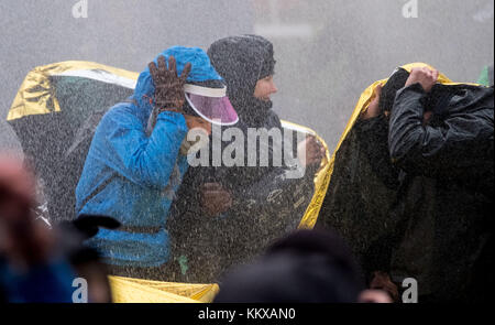 Hannover, Deutschland. Dezember 2017. Demonstranten nehmen Deckung, als das Wasser einer Polizeiwasserkanone während einer Demonstration gegen die rechtsextreme Partei Alternative für Deutschland (AfD) während des Parteitags in Hannover, Deutschland, am 2. Dezember 2017, Wasser auf sie sprüht. Quelle: Peter Steffen/dpa/Alamy Live News Stockfoto