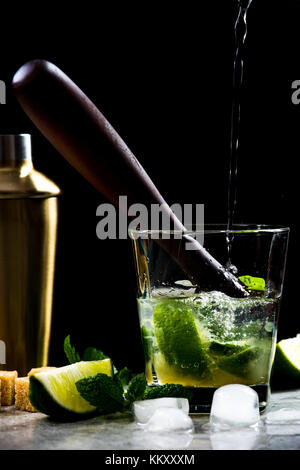 Gießen rum in mojito Cocktail auf Stein Bar, noch Leben in schwachem Licht Stockfoto